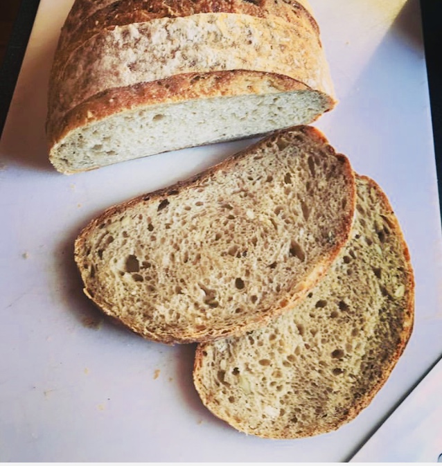 Close-up of a sliced loaf of crusty artisan bread with a warm golden crust and airy open crumb, resting on a light wooden board, painted in a soft warm watercolour style